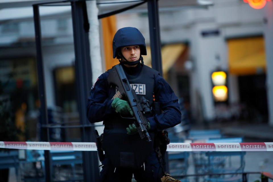 A police officer stands guard in fornt of a secured area after exchanges of gunfire in Vienna