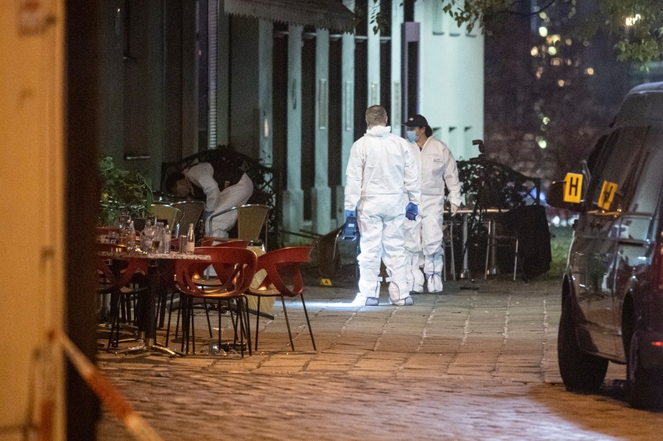 Forensics inspect abandoned tables and chairs at the scene