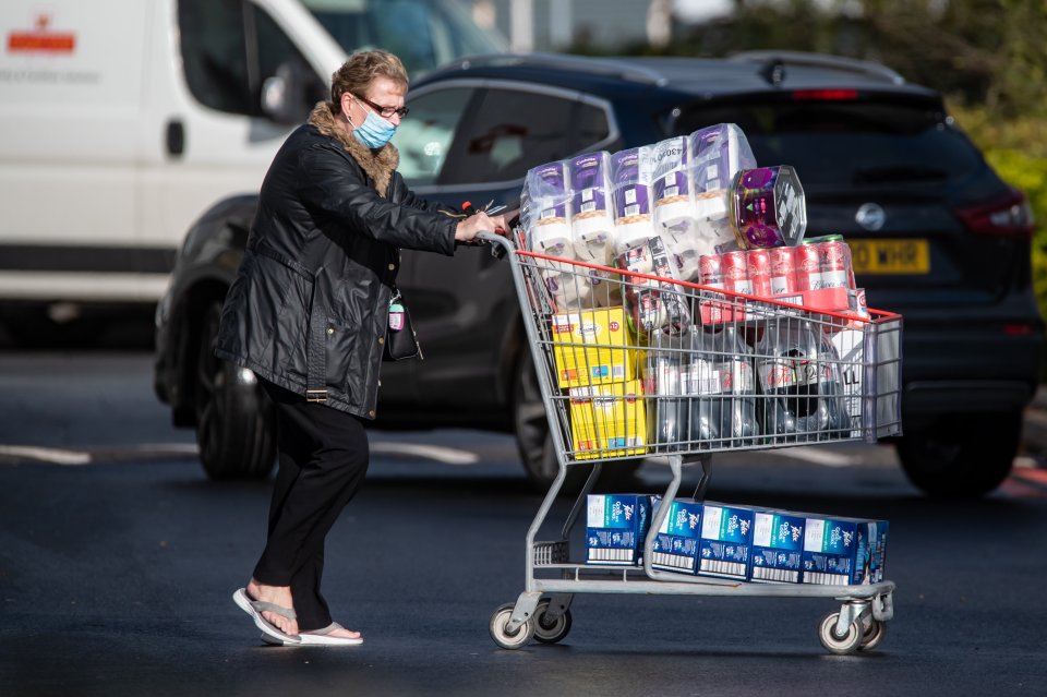 A woman leaves the store in Birmingham with bottles of drink and toilet paper