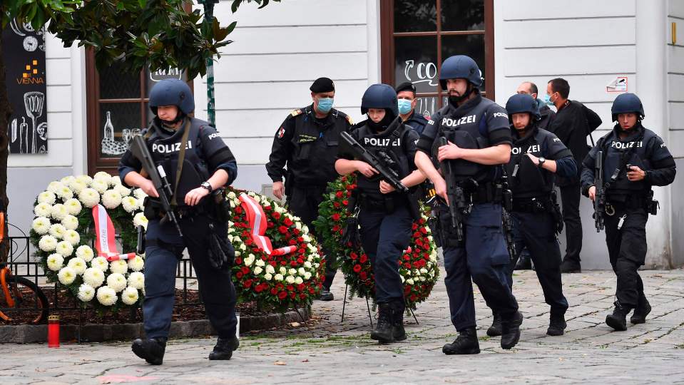 Armed police walk past wreathes laid after the attack