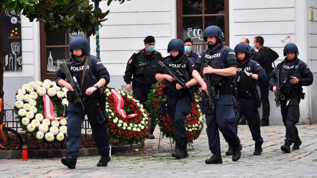 Armed police walk past wreathes laid after the attackCredit: AFP or licensors