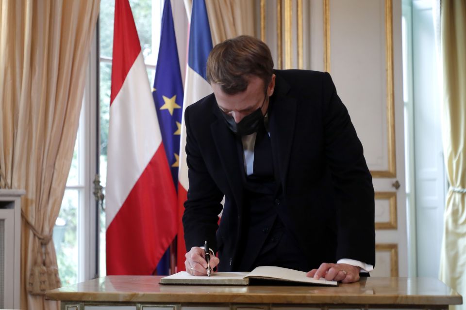 Emmanuel Macron signs a book of condolence for the four victims