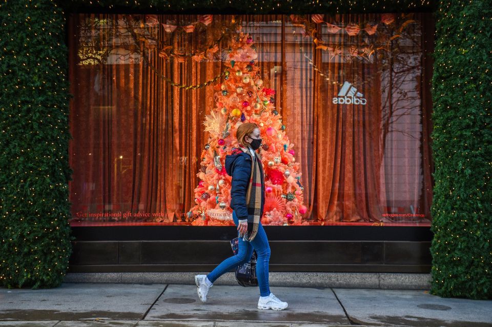 A woman wearing a face mask passes a Christmas window display on London's Oxford Street