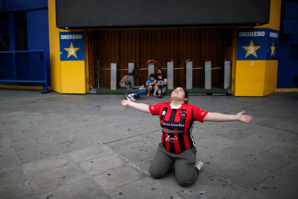 A fan mourns the death of the football legend as she kneels at the entrance of the Boca Juniors stadium known as La Bombomera, in Buenos Aires