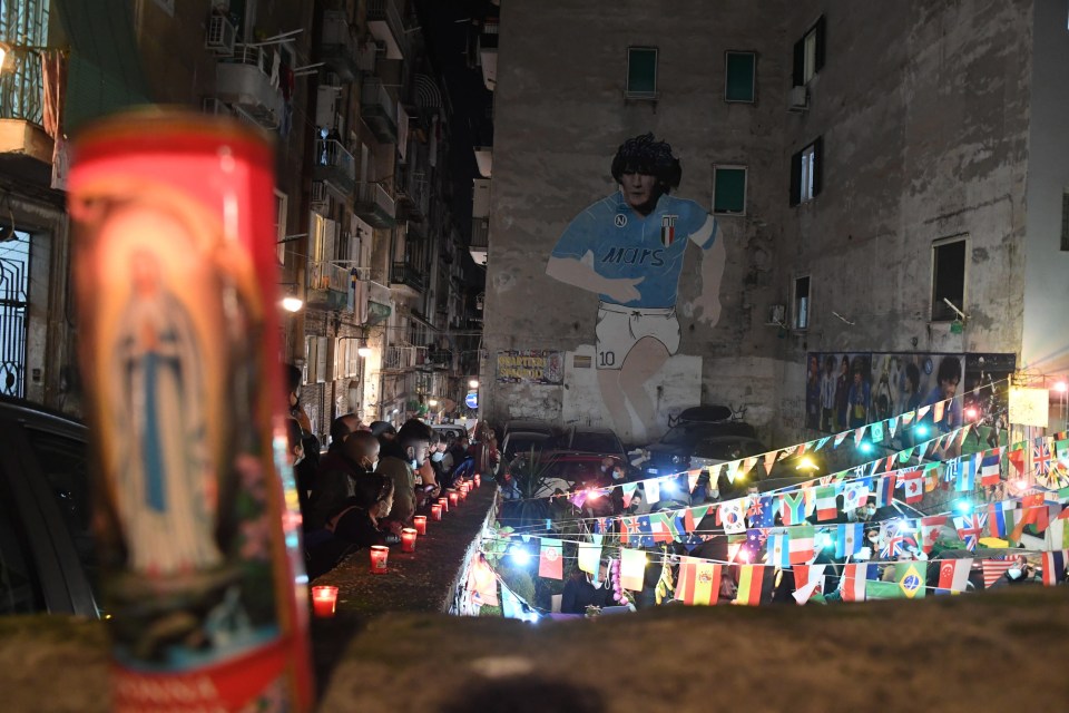 Mourners gather in front of a mural of Maradona in Naples, Italy to pay their respects 