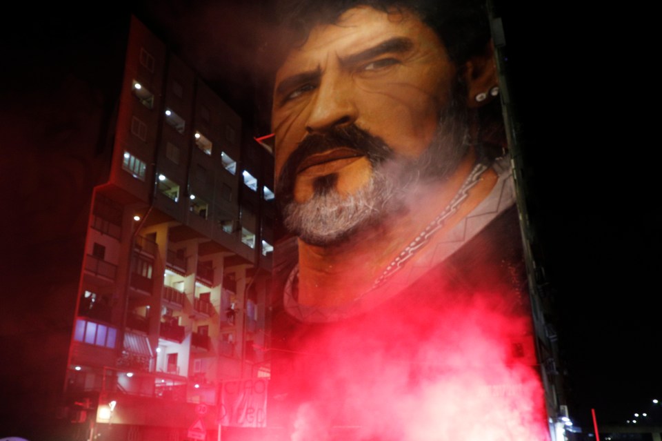 Flares illuminate a mural depicting soccer legend Diego Maradona, in Naples, Italy