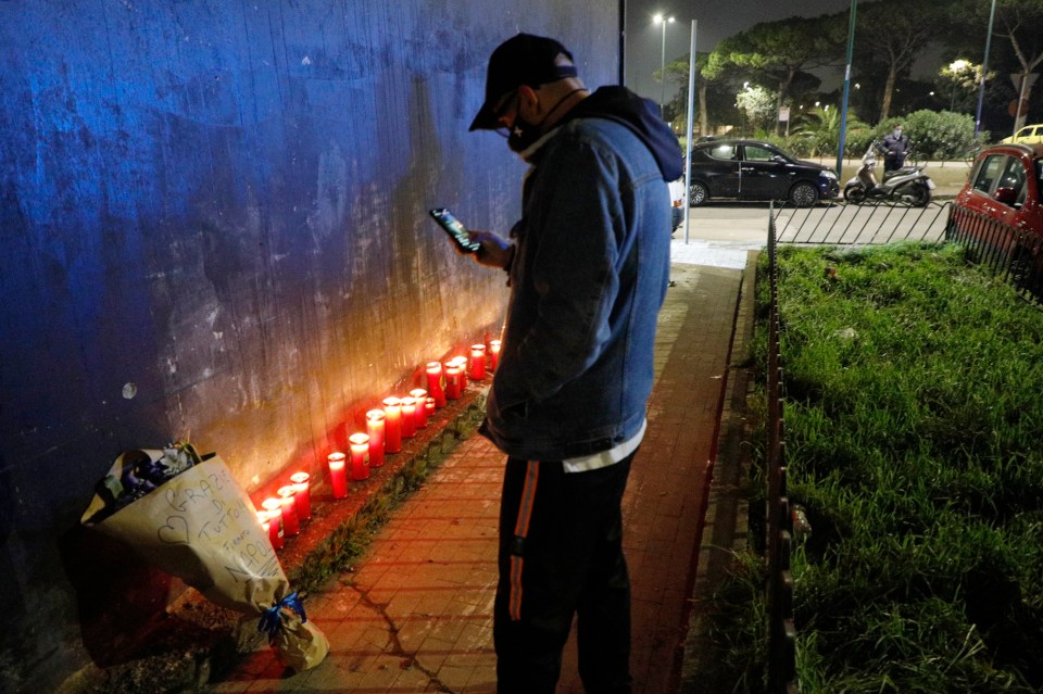 A man stands in front of candles as he pays his homage to the football legend in Naples, Italy