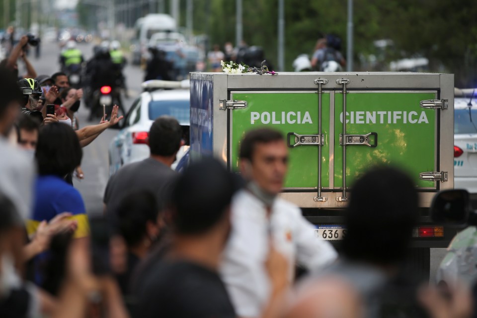 Dozens of mourners line the street as the police vehicle carrying Maradona's body drives past them in Tigre, near Buenos Aires