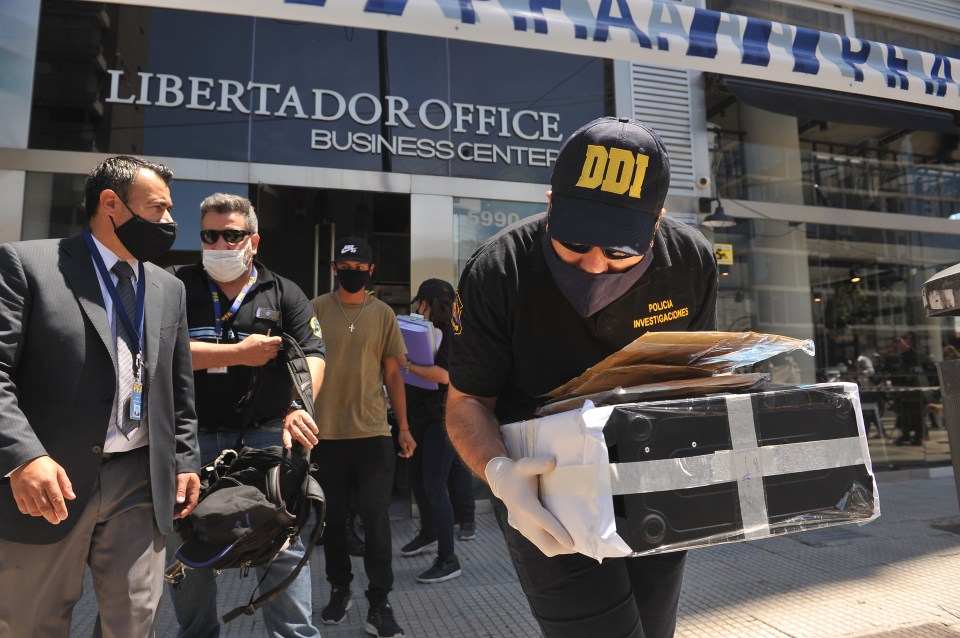 Police officers leave the doctor's office with a computer and some documents following a raid at the weekend