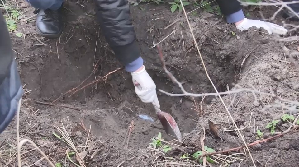 Police excavate the shallow grave in Ukraine