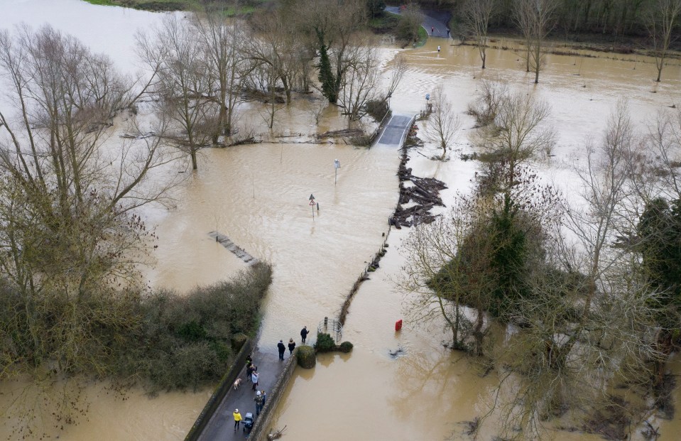 A family stand on a flooded bridge over the River Great Ouse in Pavenham