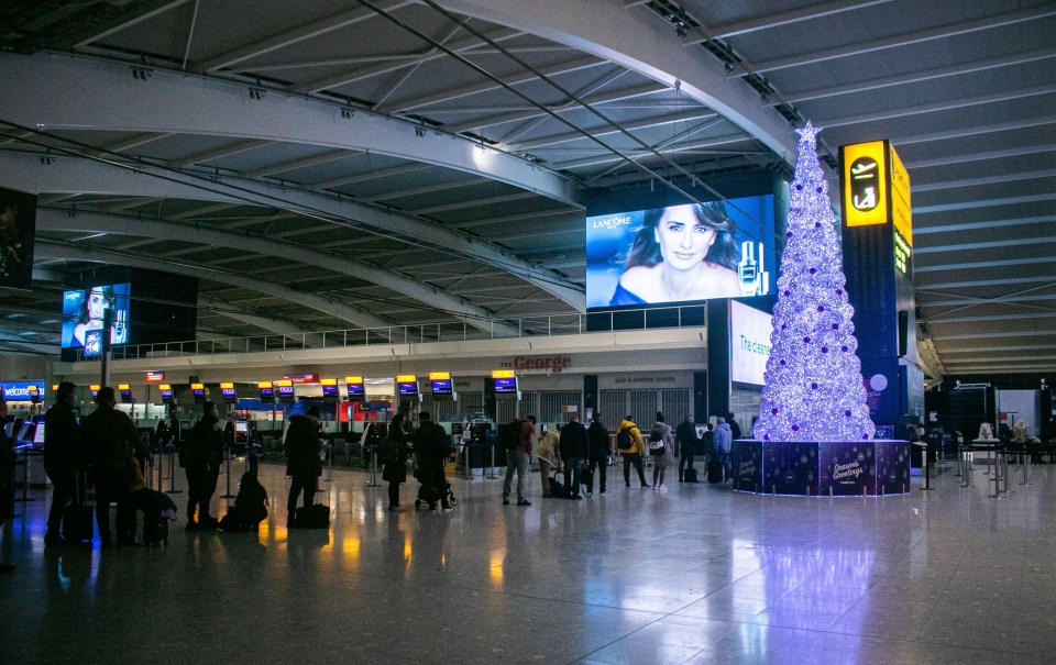 Christmas travellers waiting in line beside a large illuminated Christmas tree at Heathrow airport as many people have made preparations to leave prior to the government announcement on tier 4 restrictions