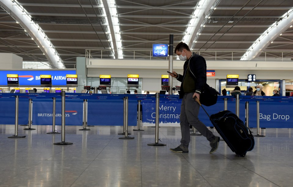 A traveller walks through an almost deserted departures hall at Heathrow Airport