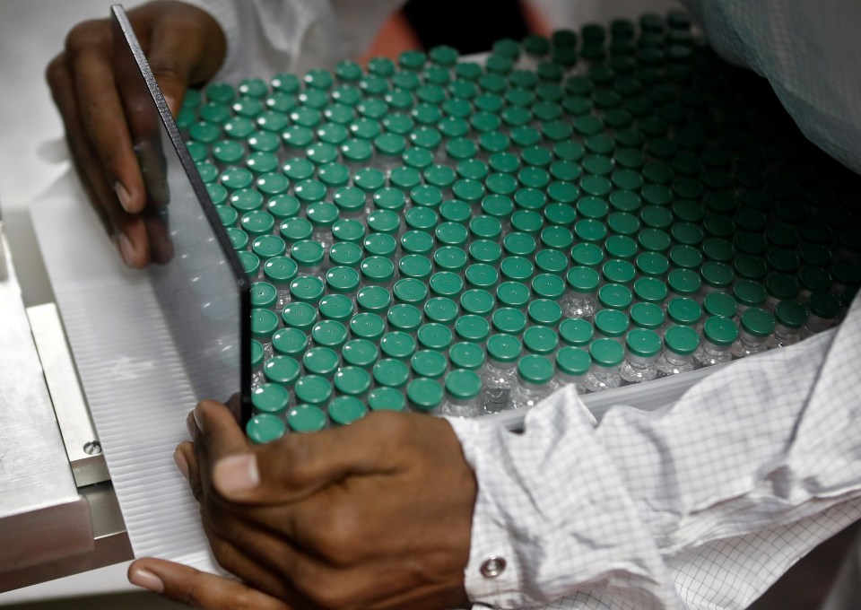 An employee removes vials of AstraZeneca's vaccine from a visual inspection machine inside a lab at Serum Institute of India, November 30