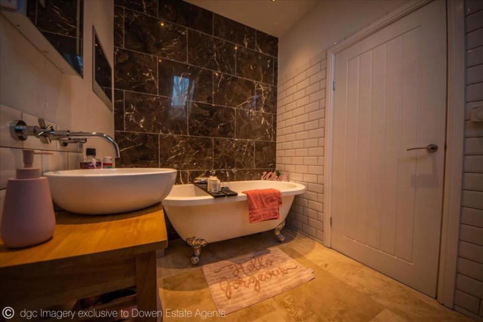 Another bathroom features marble tiles on the wall