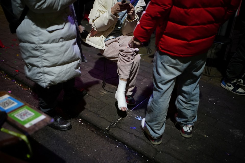 A man with an injured foot waits in line as he queues up to enter a bar 