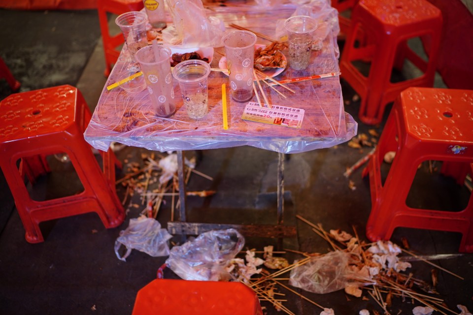 Empty cups are left on a dining table after a dinner at a street restaurant