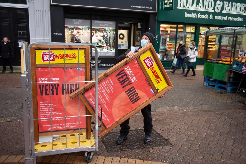 A Dartford council worker putting out very high threat level Covid posters in the high street