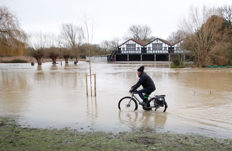 A man cycles on the embankment of the River Great Ouse after severe flooding in Bedford