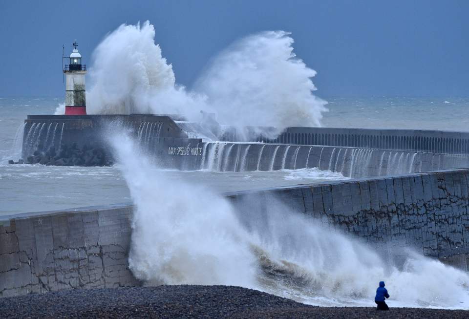 Waves crash over Newhaven Lighthouse and the harbour wall 