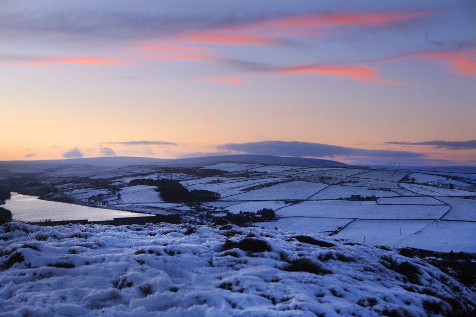 The sun goes down behind the snow covered hills at Scammonden, West Yorkshire