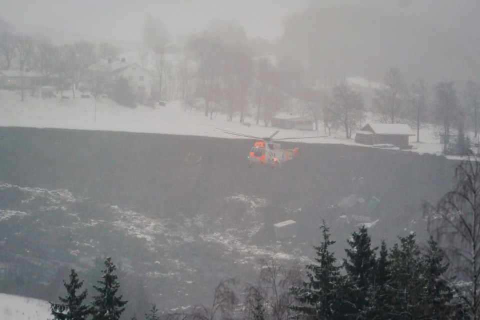 A rescue helicopter hoovers above the village of Ask