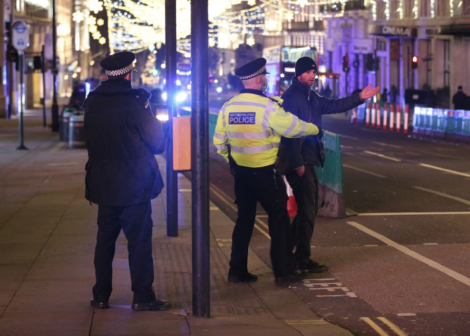 Police next to the statue of Eros in Piccadilly ask a man to move along