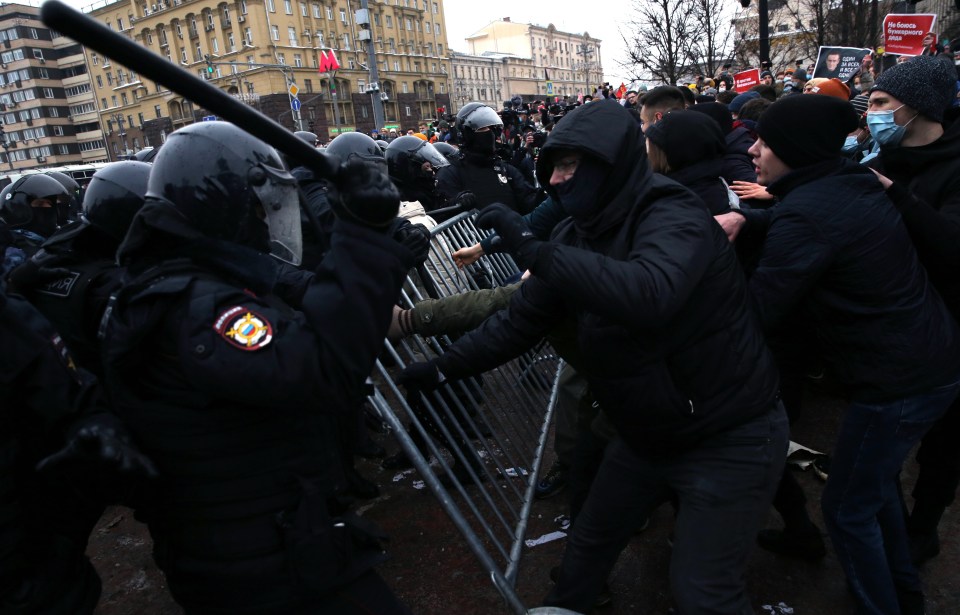 A police officer wielding a baton against a protester 