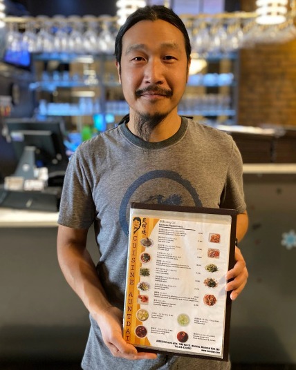 Feigang Fei holding his restaurant's menu