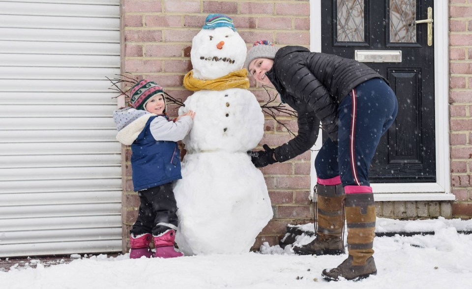 Two year old Ada Redfearn and mum Rebecca proudly display a snowman outside their home in Gateshead