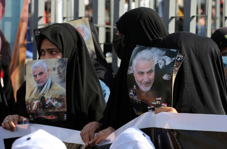 Women in Iran hold pictures of Soleimani on the first anniversary of his death