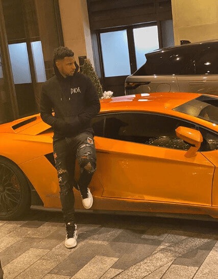 Lys Mousset standing next to his orange Lamborghini