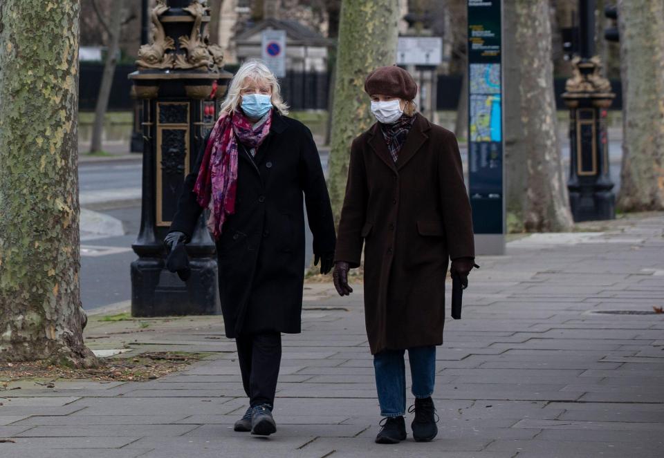 Women wearing face masks walk along the River Thames near Waterloo Bridge in London