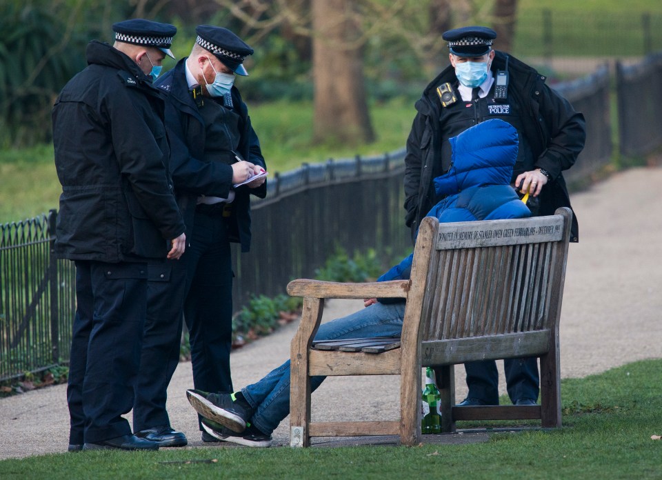 Police speak to a man at St James' park as he sits on a bench