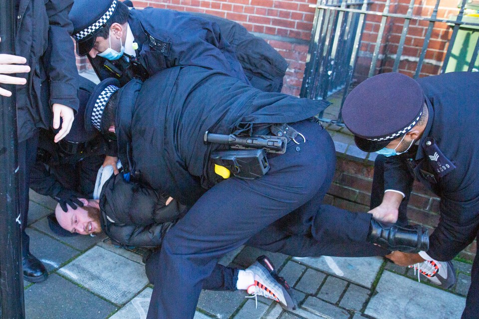 A man is held to the ground by masked officers in the Clapham Common protest