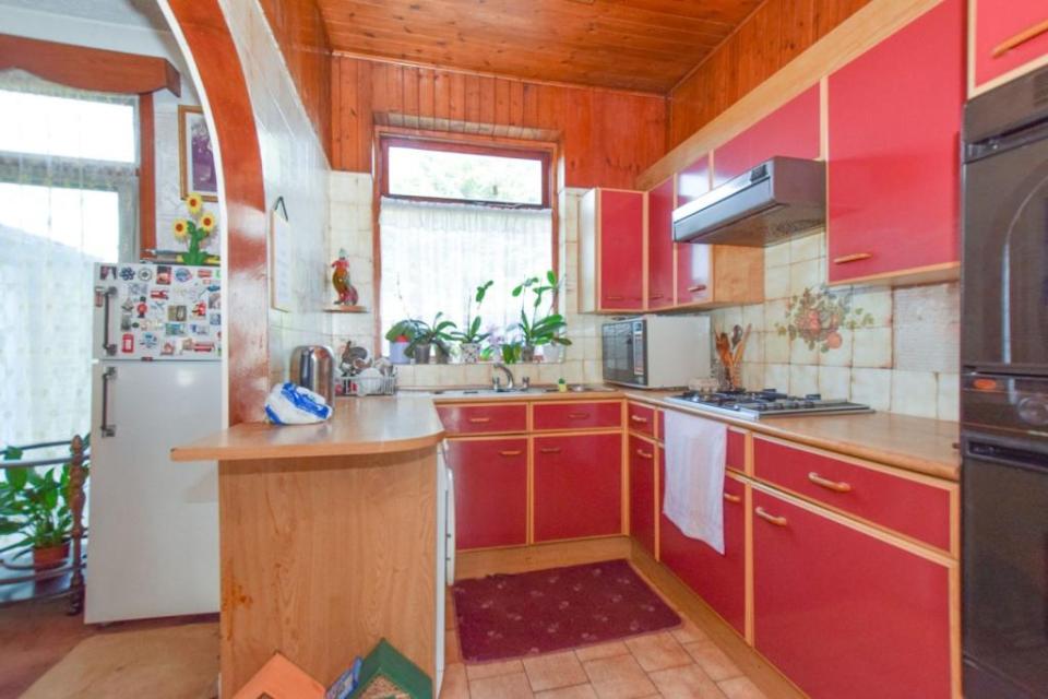 The kitchen has been lined with wood cladding and bold red cupboards