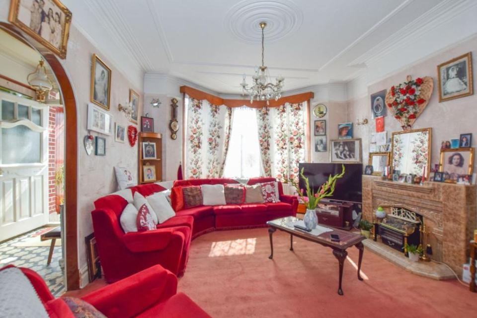 A bright red sofa is decorated with plenty of patterned and colourful pillows and matches the slightly faded red carpet