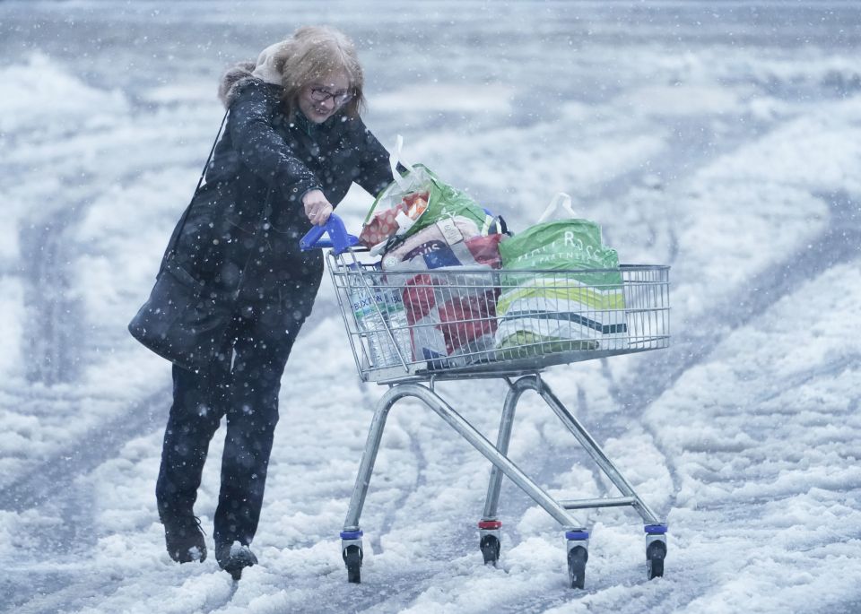 A woman pushes a shopping trolley through snow in Hexham, Northumberland