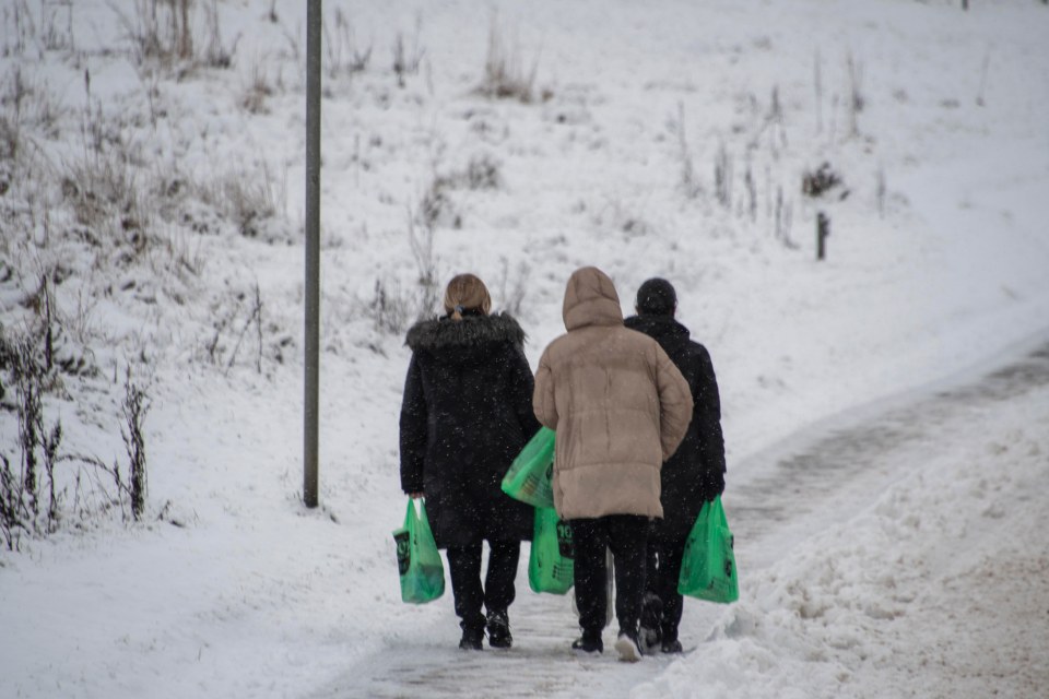 A family walks home in the snow in Glasgow with their shopping