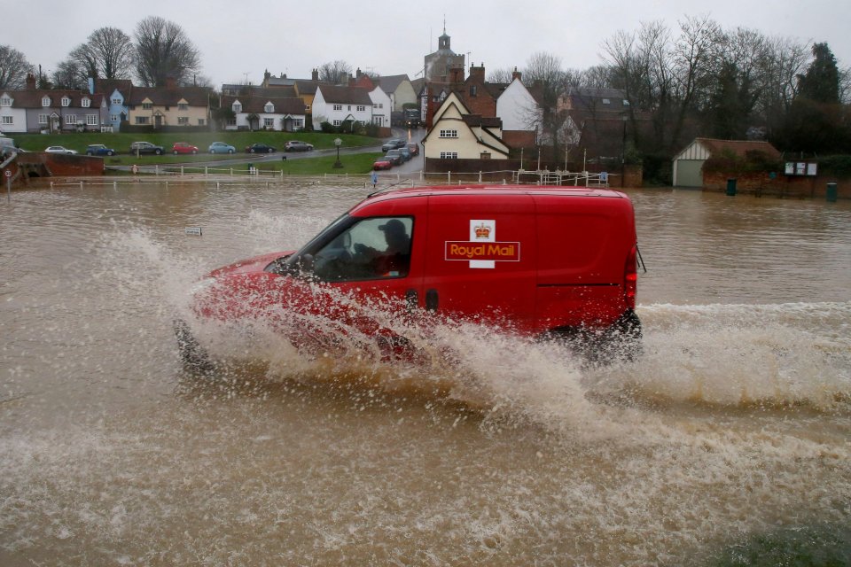 A postman made their way through flooded roads in Essex