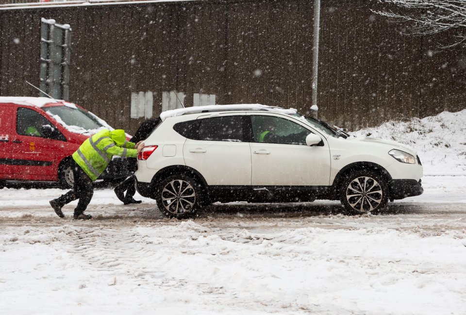 A group of people push a car up a snowy road in Halifax, in West Yorks.