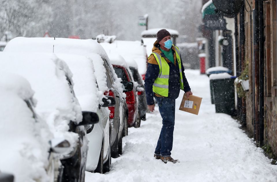 A delivery driver delivers a parcel in the snow in Scotland