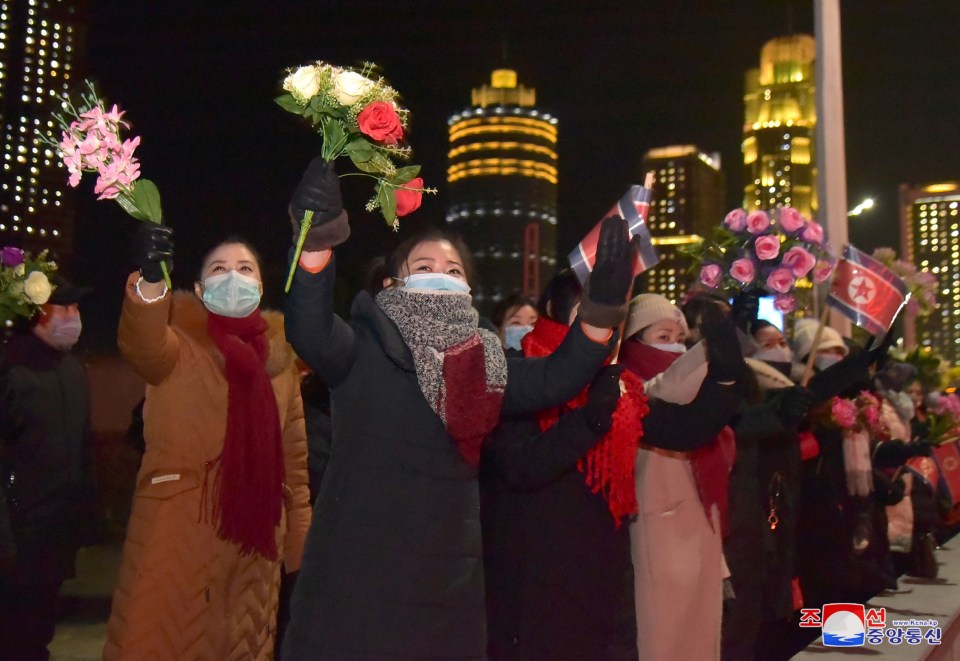 Spectators waved flowers and North Korean flags