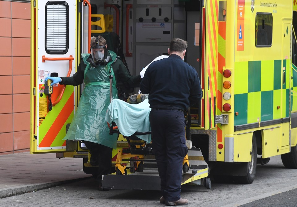 Ambulance paramedics carry a patient outside the Royal London hospital in London