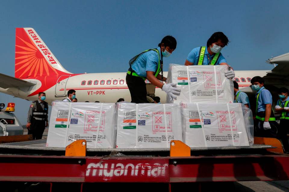 Workers unload cartons of a Covid-19 coronavirus vaccine being delivered from India to Myanmar