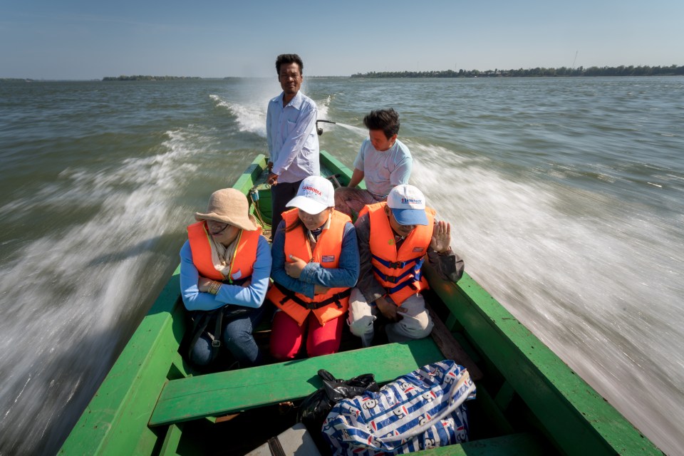 A health worker at Sambo health centre (right), on a speed boat crossing the Mekong River with his outreach health team to Koh Sam village, Sambo District, Kratie Province in 2018