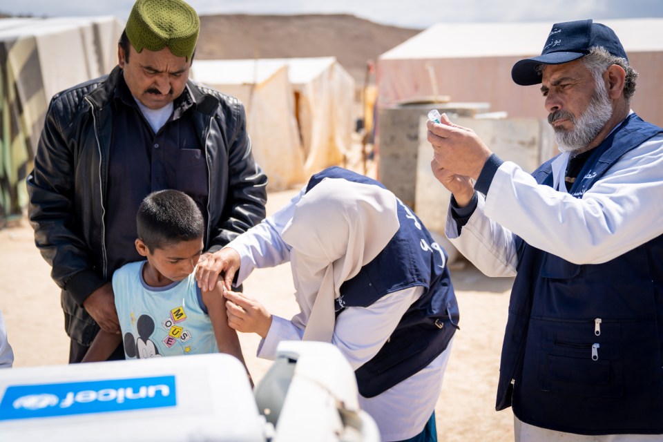 A 10-year-old is vaccinated by a mobile health team in an informal tented settlement near the Dead Sea in Jordan