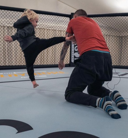 Conor Jr throwing a leg kick at his dad's head trainer John Kavanagh