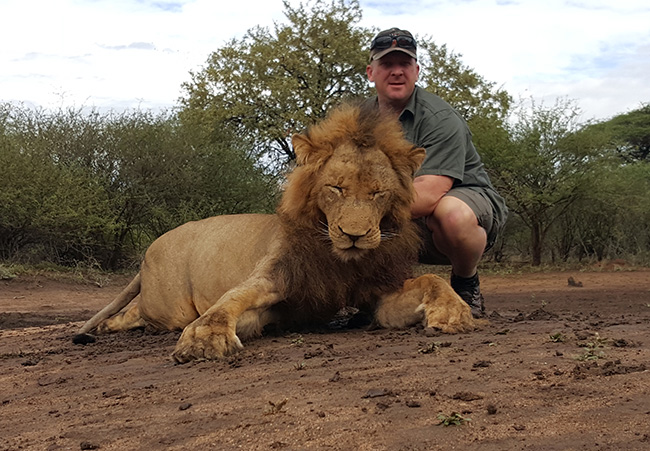 Carl Knight poses with a dead lion