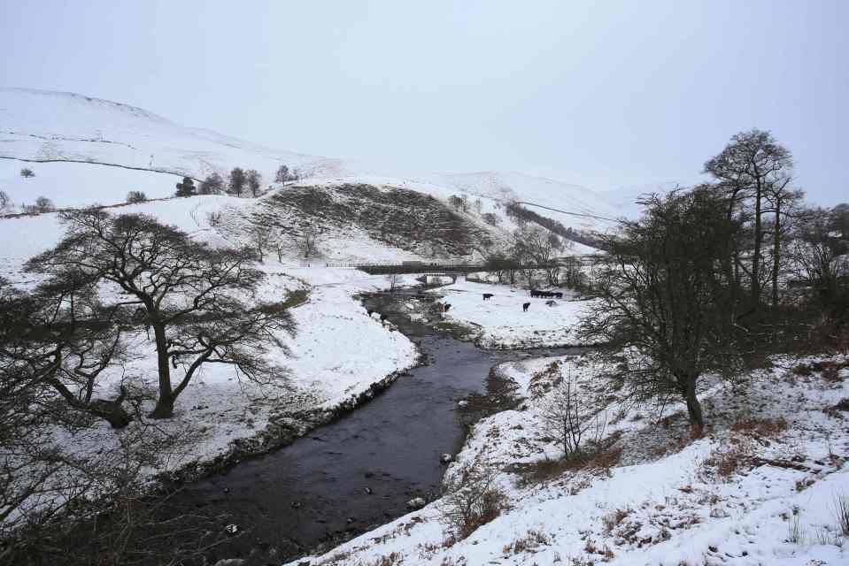 Snow covers fields alongside a stream in Sheffield